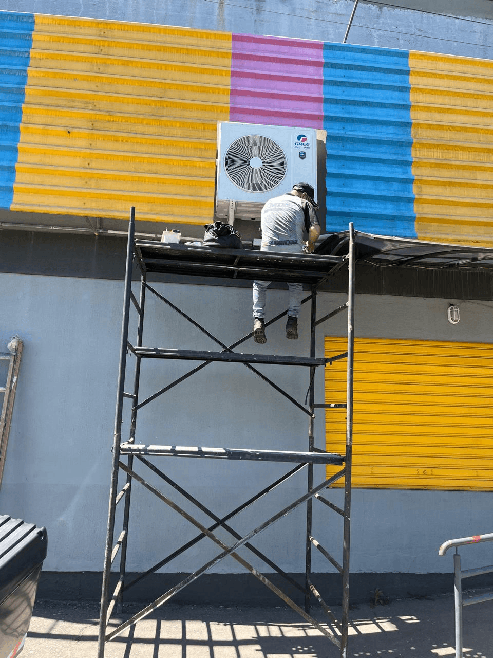 Técnico instalando condensadora de ar-condicionado em andaime