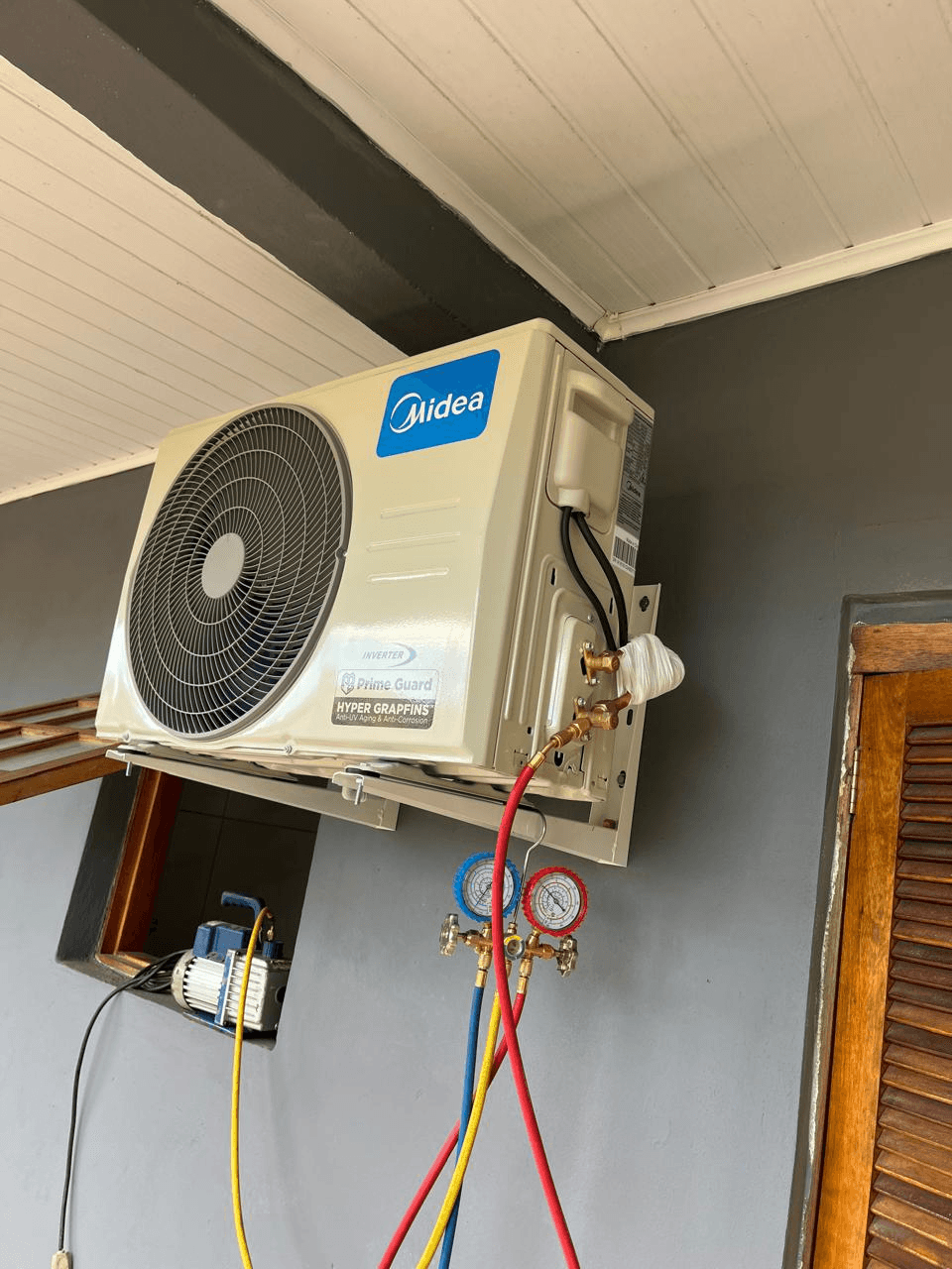 Técnico realizando manutenção em condensadora Midea com manômetros