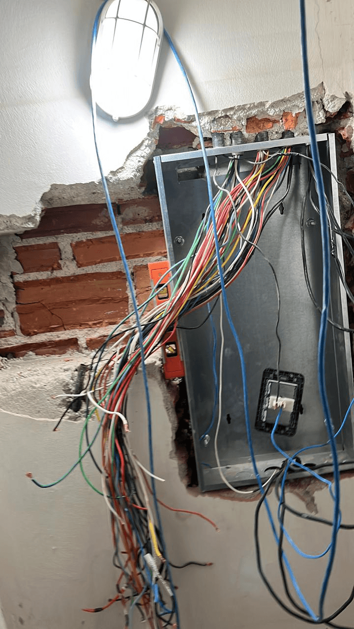 Reparo elétrico em parede com fiação exposta durante reforma